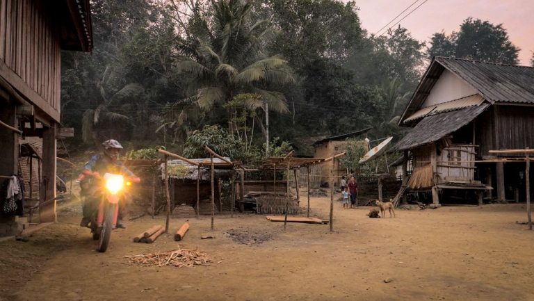 Motorbike riding through a local village in Loas.