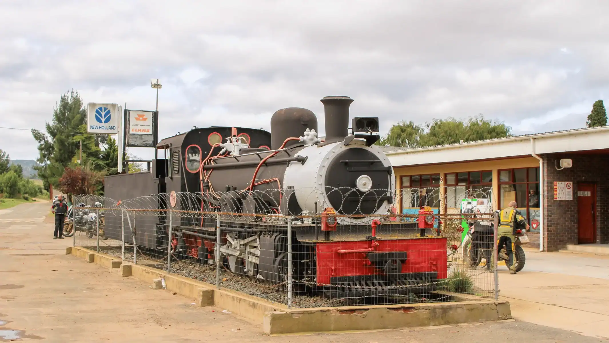 Old steam locomotive displayed on a plinth beside a building