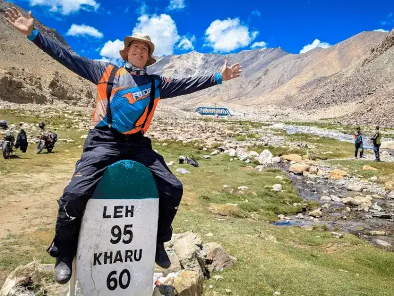 A man sitting on a milestone sign in the Himalayas