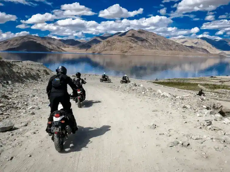 a group of motorcyclists riding alongside Pangong Tso Lake