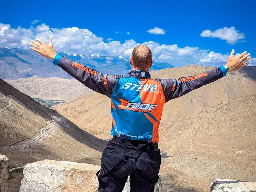 a man holding his arms wide in front of the Himalayan mountains