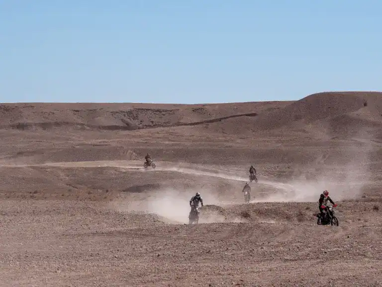 Motorcyclist riding full-throttle across open desert trails in Morocco