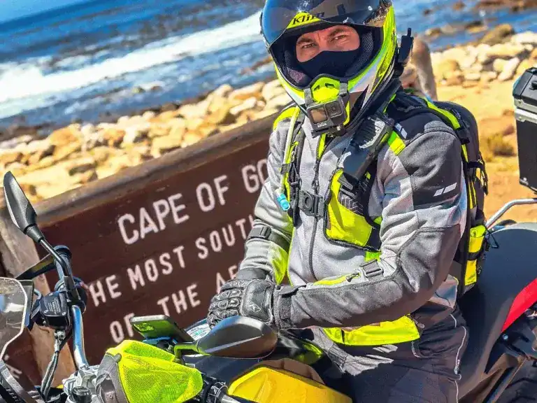 Rider standing at the Cape of Good Hope sign during the Ride Expeditions Garden Route self-guided motorcycle tour in South...